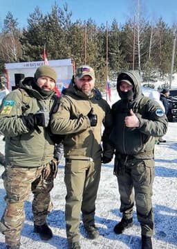Garkavenko (middle) poses for a photo with camouflage-clad men with Russian military patches on their sleeves.