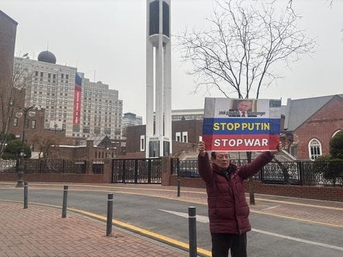 Протестующий с плакатом «Остановите Путина. Остановите войну» у российского посольства в Сеуле, 24 февраля 2026. Фото: Yonhap